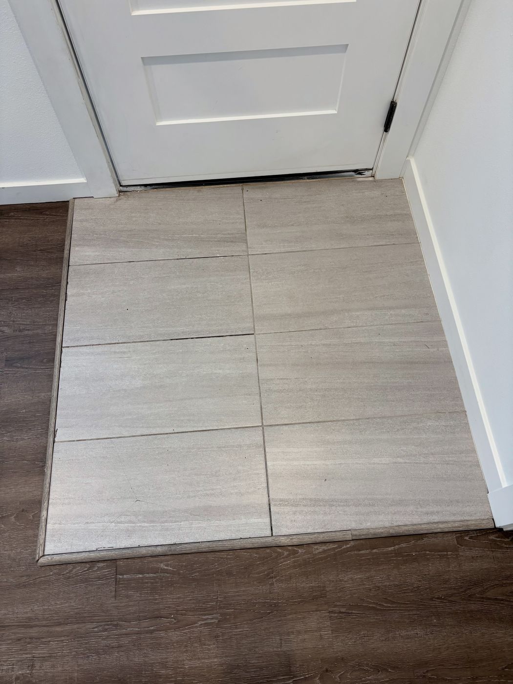 New large-format tile floor meeting wood-look flooring at a doorway