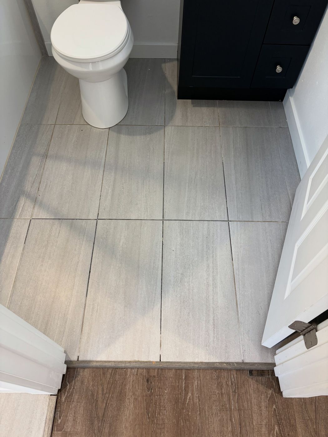 Freshly installed large-format grey tile bathroom floor